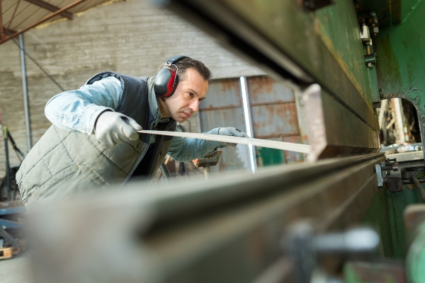 A metal worker uses one of many sheet metal fabrication techniques to mold the material.