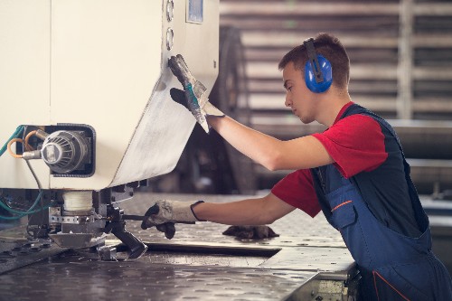 A line worker at a metal fabrication facility works on a metal product.