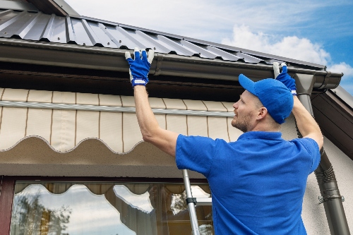 A professional gutter installer affixes a gutter to a home.