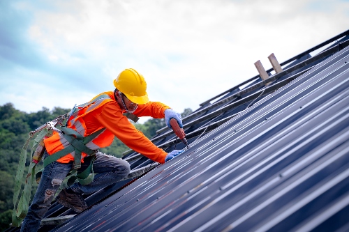 A technician installs a metal roof after his in-house team fabricated the sheet metal.