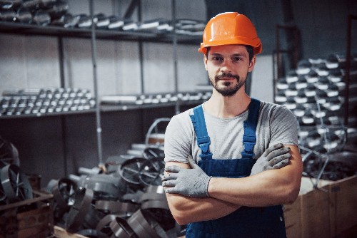 A man in overalls smiles at the camera in a local metal fabrication shop.