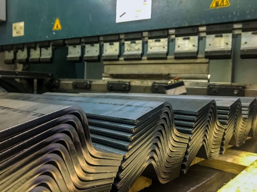 Stacks of bent metal sheet stacks sit in a sheet metal fabrication shop.